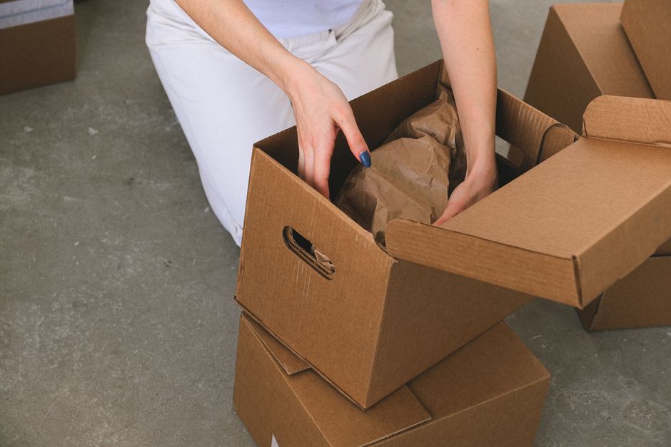 Person packing household items into sturdy cardboard boxes
