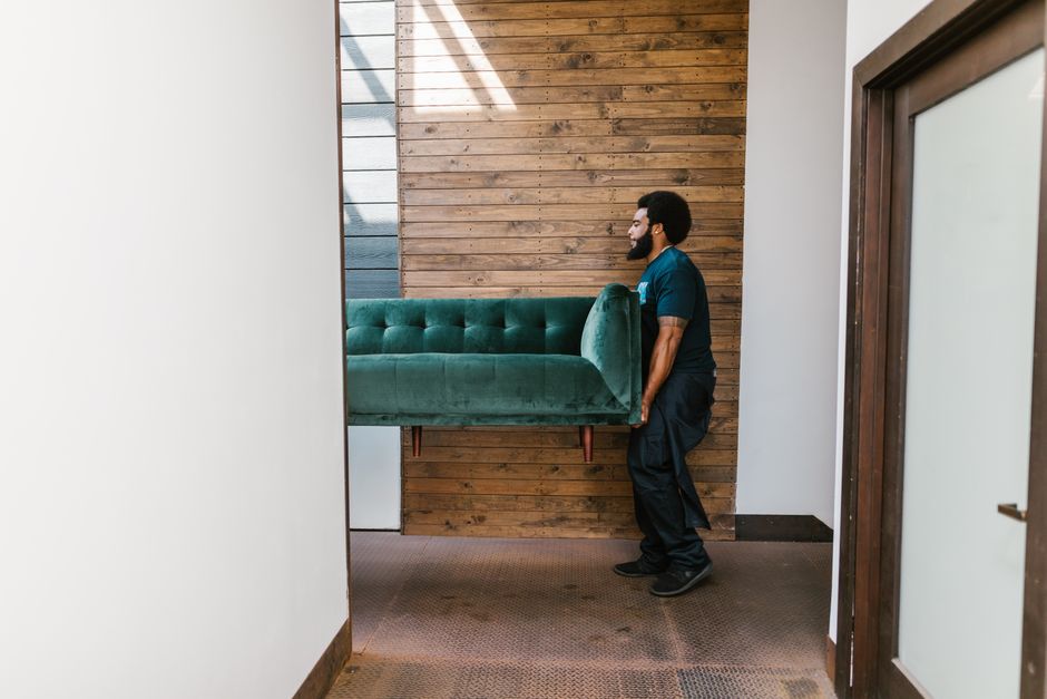 Strong movers carefully lifting and transporting heavy living room furniture